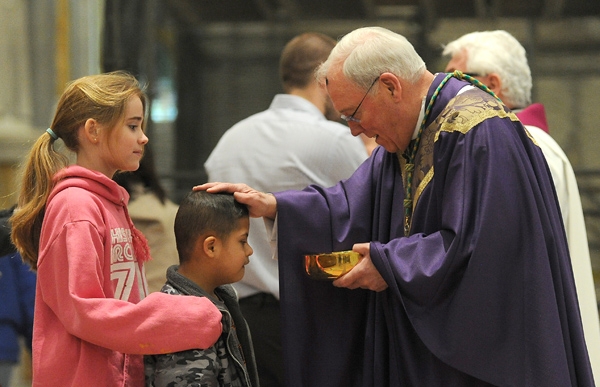 Bishop Richard J. Malone blesses 8-year-old Gabriel O'Brien of Hamburg as his 11-year-old sister Brighid looks on during Ash Wednesday Mass at St. Joseph Cathedral. (Dan Cappellazzo/Staff Photographer)